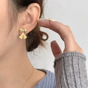 Détail d'une boucle d'oreille nœud doré avec perle sur mannequin pour un look élégant