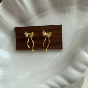 Détail de boucles d'oreilles nœud dorées élégantes sur bois sombre et céramique