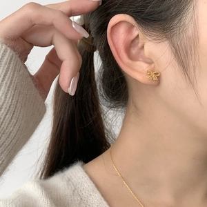 Elegant gold bow earrings with twisted texture shown on a model for a vintage aesthetic