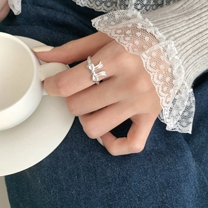 Close-up of S925 sterling silver bow ring worn on finger with elegant lace cuff