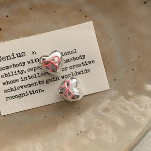 Close-up of pink bow heart earrings on a vintage card with premium metallic finish