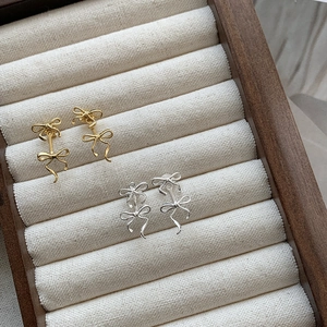 Macro detail of elegant S925 silver and gold ribbon bow earrings in a jewelry box