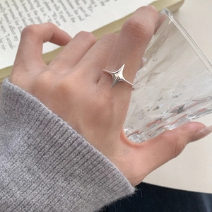 Minimalist S925 sterling silver four-pointed star ring worn on finger in aesthetic setting