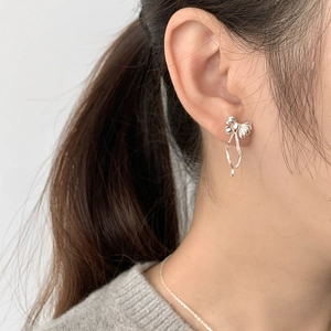 Puce d'oreille nœud en argent avec pompons élégants portée sur le lobe de l'oreille