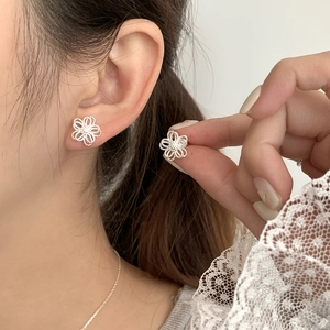 Elegant 925 sterling silver hollow flower stud earrings worn by a model in a close-up view