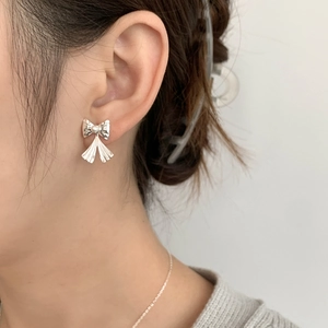 Gros plan d'une boucle d'oreille nœud en argent avec perle blanche sur l'oreille