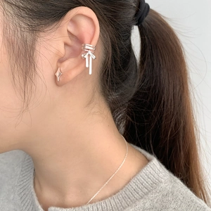 Detail of silver ballet bow ear cuff and star stud earring set on a model's ear