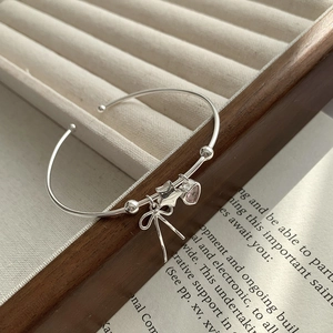 S925 sterling silver bangle featuring pink heart, star, and bow charms on wooden tray