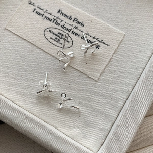 Detailed view of silver ribbon bow earrings featuring elegant twisted knot craftsmanship