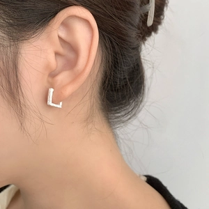Gros plan détaillé d'une boucle d'oreille géométrique en argent S925 en forme de L sur mannequin