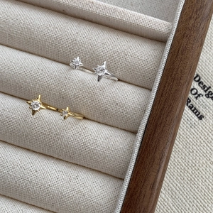 Détails de bagues étoile en argent et or avec zircons dans un écrin en lin