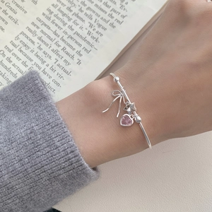 Close-up of S925 silver bracelet with pink heart, star, and bow charms on wrist