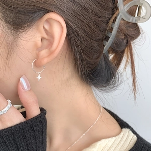 Close-up of S925 sterling silver asymmetrical hoop earrings with four-pointed star pendant