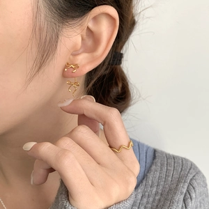 Elegant gold S925 silver bow earrings and wavy twisted ring worn by a model