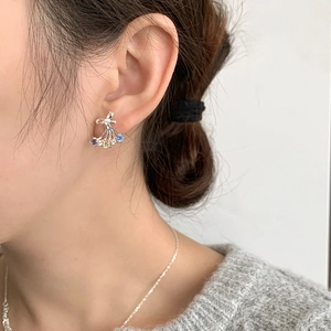 Macro detail of silver butterfly earrings with colorful zircons worn by a model