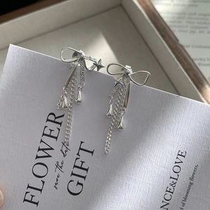 Gros plan de boucles d'oreilles nœud en argent S925 avec étoiles et pampilles délicates