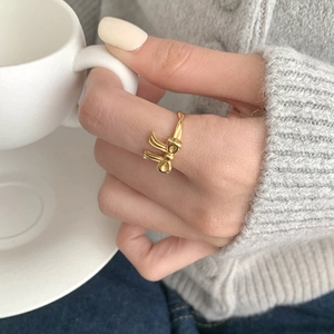 Elegant gold bow ring with adjustable opening worn by model holding a white coffee cup