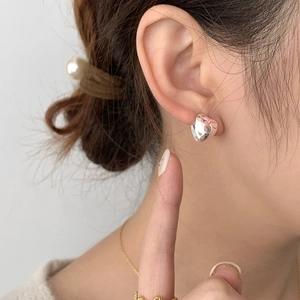 Pink ribbon heart stud earrings in S925 sterling silver on model ear closeup