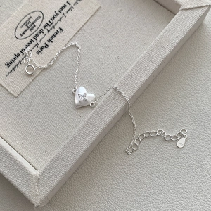 Macro shot of S925 sterling silver heart bracelet with zircon inlay on a textured tray