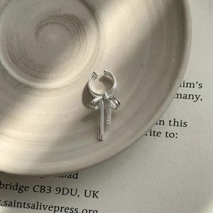 Close-up of S925 sterling silver bow ear cuff with hallmark on a decorative tray