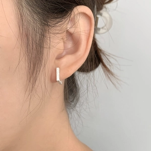 Détail macro de boucles d'oreilles géométriques en argent serties de zircons brillants