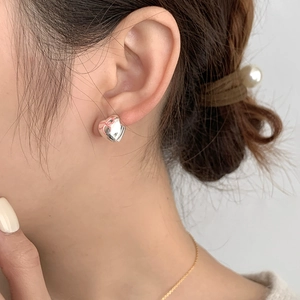 Close-up of a S925 silver heart stud earring with a red ribbon bow on a model's ear