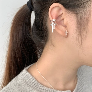 Detail of silver ribbon bow ear cuff with elegant tassels on female model's ear