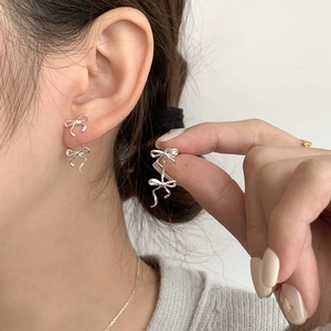 Detailed view of silver bow earrings with flowing ribbon design on sterling silver studs
