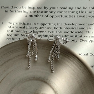 Gros plan sur les boucles d'oreilles nœud en argent S925 avec étoiles et glands