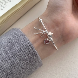 S925 silver bracelet with pink heart gem, bow and star charms on model's wrist