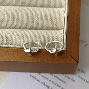 Detail of silver S925 star-shaped hoop earrings on a beige velvet jewelry box tray