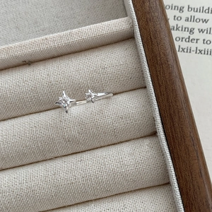 Gros plan d'une bague étoile en argent S925 avec zircons dans un écrin en velours beige