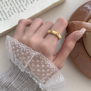 Macro detail of gold vintage lace ring with fine stripes and zircons on finger