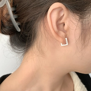 Gros plan de boucles d'oreilles carrées géométriques avec texture argentée mate sur un modèle
