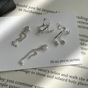 Boucles d'oreilles nœud et étoile en argent S925 sur carte blanche avec décor de livre ancien