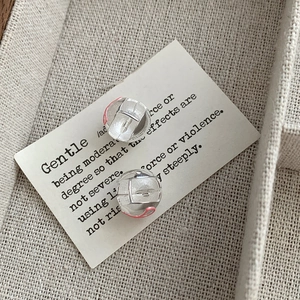 Macro shot of S925 silver sphere earrings with matte texture and red enamel stripes