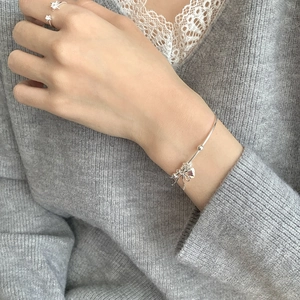 Close-up of S925 sterling silver bow charm bracelet and star ring on a model