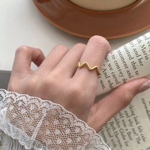 Détail d'une bague en argent S925 doré 18 carats au motif vague portée au doigt