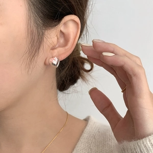 Pink bow heart stud earrings in silver finish worn by a model in a close-up shot