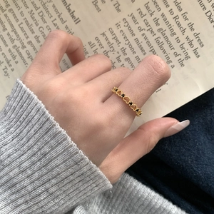 Vintage gold hollow heart ring with black cubic zirconia on stylish magazine background