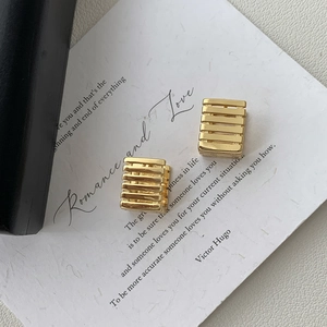 Detailed view of golden geometric hollow square earrings on a white aesthetic card