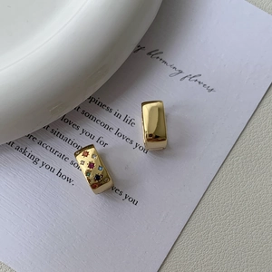 Detail of gold eight-point star earrings featuring colorful zircon stones on art card