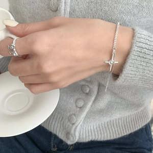 Close-up of S925 silver four-pointed star bracelet and bow ring on a model with a coffee cup