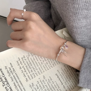 S925 silver bracelet with pink heart and bow charms worn with a star-studded ring
