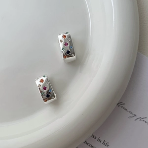 Minimalist 925 silver earrings with colorful zircon starburst inlays on ceramic plate