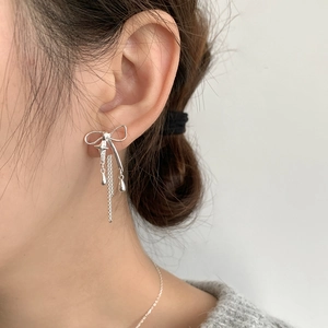 Détail de boucles d'oreilles nœud en argent S925 avec étoiles et gouttes sur mannequin