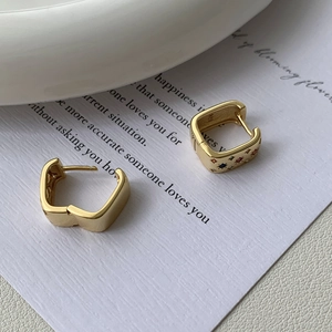 Macro detail of gold 925 silver square earrings with rainbow cubic zirconia stones