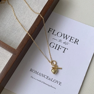 Close-up of gold heart pendant necklace with toggle clasp on wooden tray