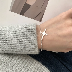 Close-up of a silver S925 four-pointed star bracelet worn on a wrist over a grey sweater
