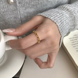 Detail of hollow heart ring in gold finish featuring black cubic zirconia on finger